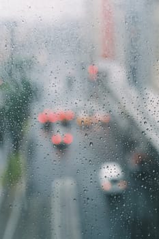 looking through a glass window, with raindrops and busy traffic.