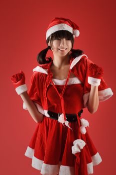 Happy smiling Christmas girl dancing against red background.
