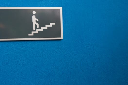 Sign showing character on stairs on blue wall.