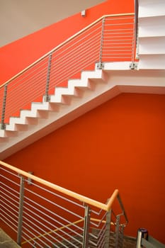 Staircase with red wall and fence going upstairs.