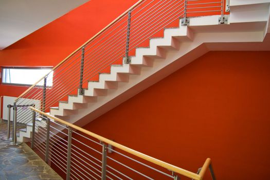 Staircase with red wall and fence going upstairs.