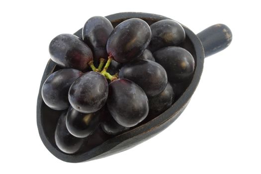 bunch of black grapes on a rustic wooden scoop isolated on white