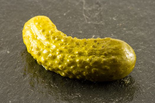 Single pickled gherkin on black slate