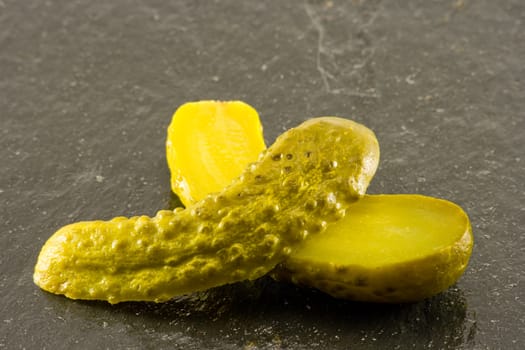 Single sliced pickled gherkin on black slate