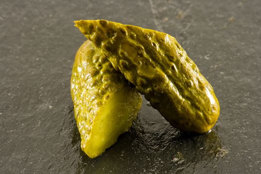 Pickled gherkin cut in half on black slate
