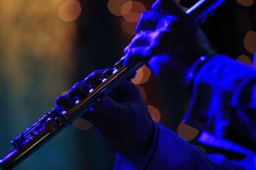 Flute in hands of the musician with scenic light