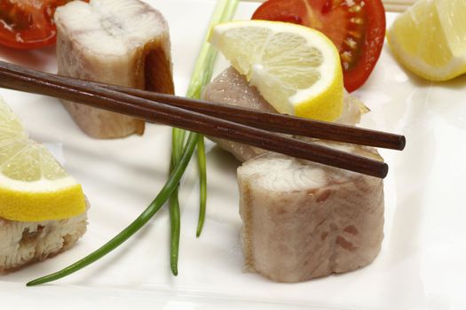 Pieces of smoked eel on a plate with garnish