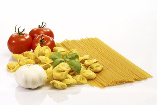 Raw spaghetti and tortellini with basil and tomatoes