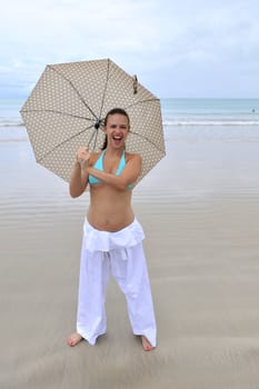 woman jumping on a tropical beach holding an umbrella 
