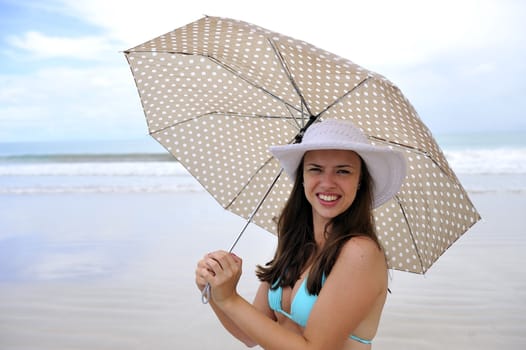 woman jumping on a tropical beach holding an umbrella 
