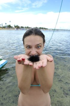 Woman holding an urchin on the beach in Brazil
