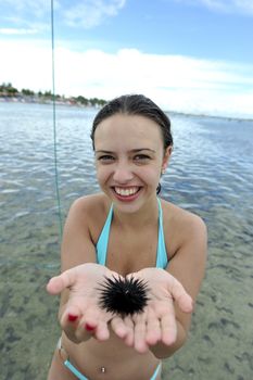 Woman holding an urchin on the beach in Brazil
