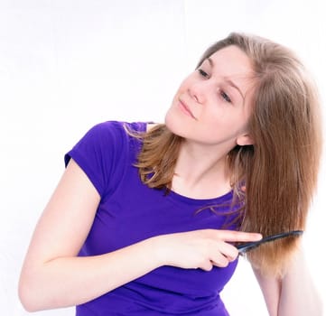 Studio Shot of a beautiful girl in a blue t-shirt dressing her hair, isolated on white background