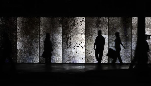 Silhouette of sidewalk pedestrians at night