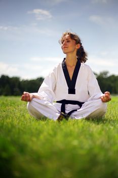 beautiful girl in kimono meditating on green grass