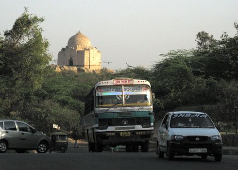 A view of New Delhi: a CNG bus, with an old tomb behind.