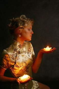 The beautiful blonde with candles on a dark background