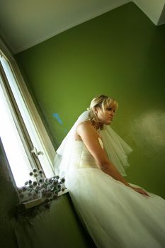 Beautiful girl in a wedding dress at a window with chrysanthemums