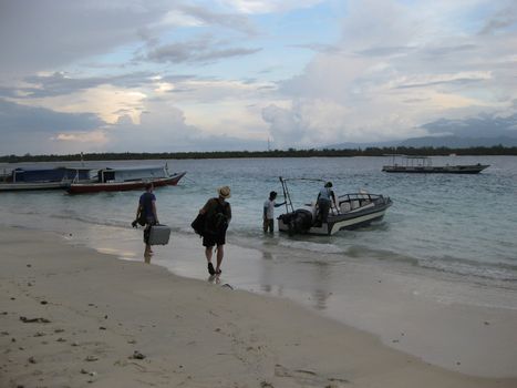 Two friend's carrying their luggage to the boat as they leave the Island following a holiday.