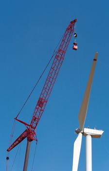 People make repairs wind turbines with the help of a crane