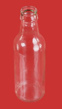 Glass empty bottle on the red background