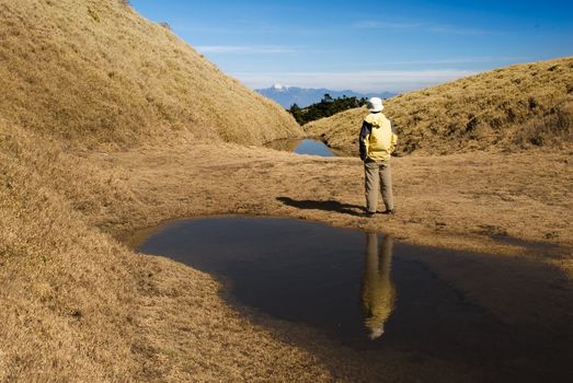 Watching mountain stand on golden grassland lake in morning.