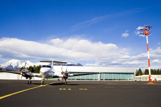 Small airplane on runway with hangar in background.