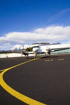 Small airplane on runway with hangar in background.