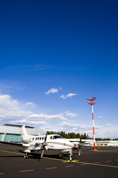 Small airplane on runway with hangar in background.