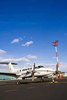 Small airplane on runway with hangar in background.