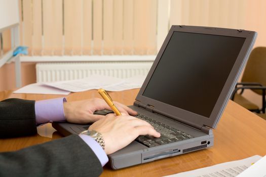 The laptop and man's hands with a pen