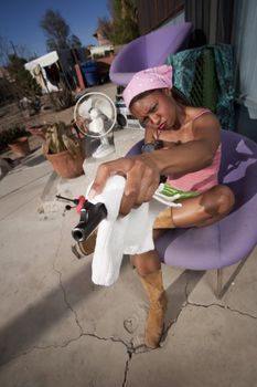 Black woman cleaning rifle in front of house with messy yard