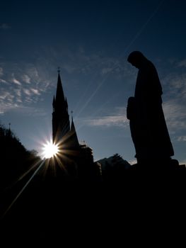 Silhouette of the Basilica of the Immaculate Conception in Lourdes with statue of the virgin Mary
