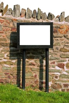 an empty billboard standing in front of a wall in sunshine.