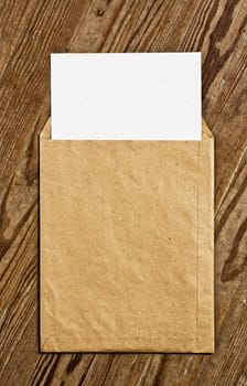 Open Brown Vintage Envelope, with white paper, over wooden surface.