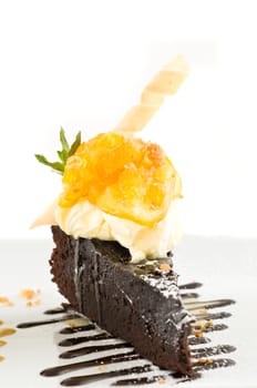 Slice of chocolate cake with cream, fruit, and mint.