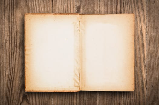 Vintage book, open, on old wooden table.