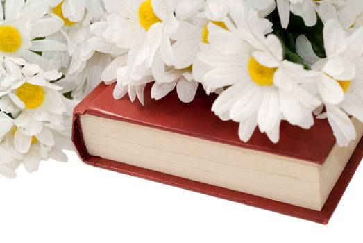 Closeup view of a romance novel with some fake daisies sitting on top, isolated against a white background