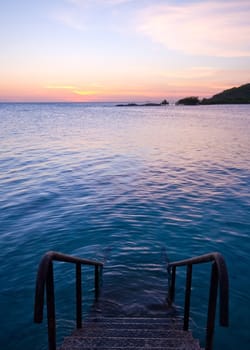 natural sea swimming pool with staircase and sunset
