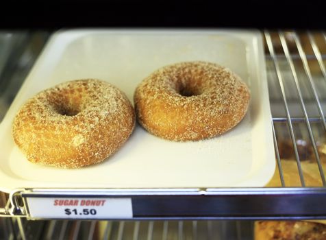 Two doughnuts on a tray in a show-window with the price