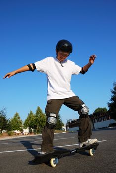 Teenage boy having fun skateboarding on a parking lot on a sunny day.