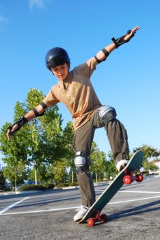 Teenage boy balancing on a skateboard in a parking lot on a sunny day with blue sky and trees in the background.