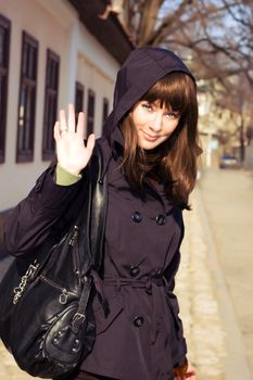 Beautiful brunette in coat and hood saying hello