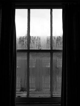 Urban scene seen through a window in a rainy day in black and white