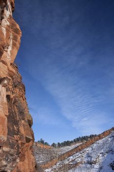 vertical red sandstone cliff framing blue sky in Colorado Rocky Mountains, winter scenery with snow