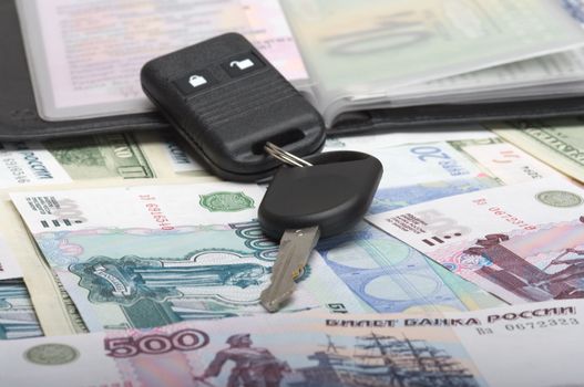 Black wallet with autodocuments and a car key on denominations.