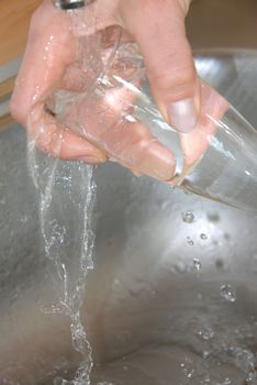 hand washing wineglass in water in sink