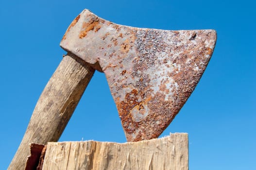 Photo of a rusty ax against the blue sky.