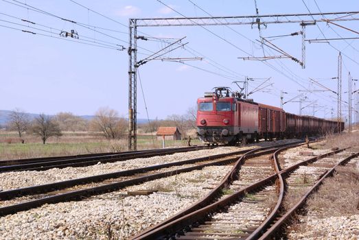 Red old train on a railroad passing by.