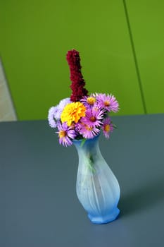 flowerpot full of summer flowers on a gray table